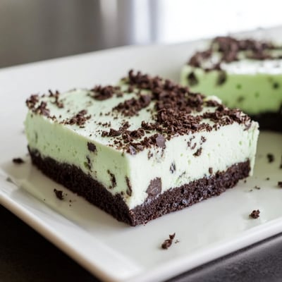 A single Mint Chocolate Chip Cheesecake Bar is lifted with a fork, ready to serve at a summer gathering.