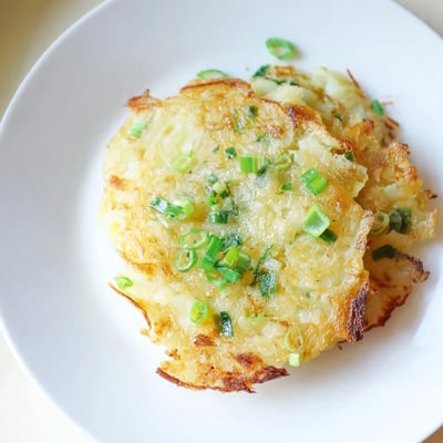 A rustic stack of Irish Potato Cakes with Scallions served alongside poached eggs and smoked salmon.